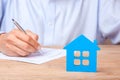 Concept home insurance, rent or purchase. Blue house and Man signs contract in the Royalty Free Stock Photo