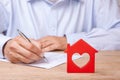 Concept home insurance, rent or purchase. Red house with heart and man signs contract Royalty Free Stock Photo