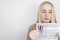 The girl on a white background reads the instructions for medicines. The woman looks at the list and composition of the drug. The