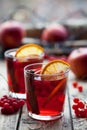 The concept of homemade mulled wine. Sangria or punch with orange, apple and berries in a glass on wooden table.