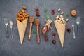 Concept for homemade various nuts ice cream. Mixed nuts in waffle cones ,metal utensils and honey dipper on dark concrete