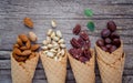 Concept for homemade various nuts ice cream. Mixed nuts in waffle cones on shabby wooden background.top view