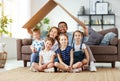 Concept of housing and relocation. happy  big family mother father and kids with roof at home Royalty Free Stock Photo