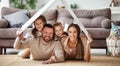 Concept housing  young family. mother father and children under fake roof in  new home Royalty Free Stock Photo