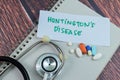 Concept of Huntington\'s Disease write on sticky notes with stethoscope isolated on Wooden Table