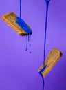 Concept idea : blue liquid paint flows down on slices of dark bread on violet background