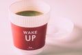 Concept idea, close up a take away cup of hot coffee that it have the word `wake up` in morning on white background.