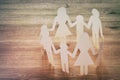 concept image of Family paper chain cutout holding hands, over wooden table.