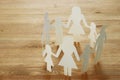 concept image of Family paper chain cutout holding hands, over wooden table.