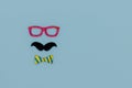 Concept image with glasses, moustache and bow tie on light blue background as resource for creative projects, copy space on the