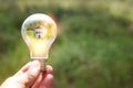 Concept image of a light bulb and small house in nature. Idea of ecology, solar energy, and sustainability Royalty Free Stock Photo