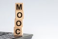 Concept image a wooden block and word MOOC on white background. The cubes are located on the keyboard. Selective focus.