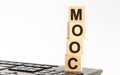 Concept image a wooden block and word MOOC on white background. The cubes are located on the keyboard. Selective focus