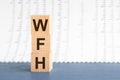 Concept image a wooden block and word WFH - Work From Home - with shadow selective focus a row of blocks is located on a grey Royalty Free Stock Photo