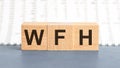 Concept image a wooden block and word WFH - Work From Home - with shadow selective focus a row of blocks is located on a notepad. Royalty Free Stock Photo