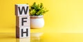 Concept image a wooden block and word - WFH - WORK FROM HOME on yellow background Royalty Free Stock Photo