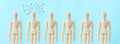 Concept image of wooden figures standing together, one persion looking upset, tired, and anxious