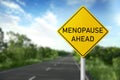 Concept of impending climacteric. Sign MENOPAUSE AHEAD near asphalt road outdoors Royalty Free Stock Photo