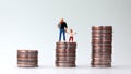 Miniature men and miniature children standing on a pile of coins. Royalty Free Stock Photo