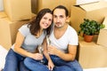 Young couple celebrating, sitting among boxes, drinking champange and plannig how they will furnish their new house.