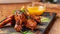 The concept of Indian cuisine. Baked chicken wings and legs in honey mustard sauce. Serving dishes in the restaurant on a black Royalty Free Stock Photo