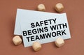 On a brown surface, wooden cubes and a business card with the inscription - Safety Begins with Teamwork