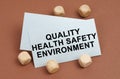 On a brown surface, wooden cubes and a business card with the inscription - quality health safety environment