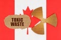 On the flag of Canada, the symbol of radioactivity and torn cardboard with the inscription - Toxic waste Royalty Free Stock Photo