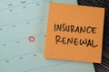 Concept of Insurance Renewal write on sticky notes with calendar isolated on Wooden Table Royalty Free Stock Photo