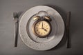Concept of intermittent fasting, ketogenic diet, weight loss. fork and knife, alarmclock on plate Royalty Free Stock Photo