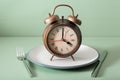 Concept of intermittent fasting, ketogenic diet, weight loss. fork and knife, alarmclock on plate Royalty Free Stock Photo