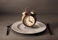 Concept of intermittent fasting, ketogenic diet, weight loss. fork and knife on a plate and alarmclock Royalty Free Stock Photo