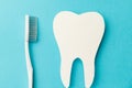 The concept of the International Day of the Dentist. A white toothbrush and a paper tooth on a blue background Royalty Free Stock Photo