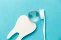 The concept of the International Day of the Dentist. White toothbrush, paper tooth and glass globe on a blue background Royalty Free Stock Photo