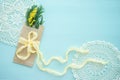 Concept of International women`s day mimosa brunch in Kraft envelope bag on blue background, yellow silk bow, text, crochet doily