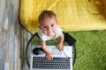 Concept of internet for children. top view: a cute funny little baby girl is standing in front of a laptop, putting hand Royalty Free Stock Photo