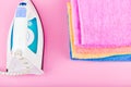 The concept of ironing clothes. House order. Iron and ironed fabric. Electric iron on a pink background with towels. multi-colored Royalty Free Stock Photo