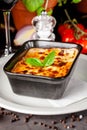 The concept of Italian cuisine. Baked lasagna in a black ceramic baking dish. The chef decorates the dish in the restaurant