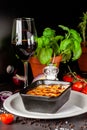 The concept of Italian cuisine. Baked lasagna in a black ceramic baking dish. The chef decorates the dish in the restaurant