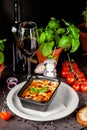 The concept of Italian cuisine. Baked lasagna in a black ceramic baking dish. The chef decorates the dish in the restaurant