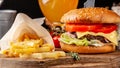 The concept of Italian cuisine. Italian burger with french fries on a wooden board and a glass of light beer with foam Royalty Free Stock Photo