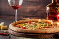 Concept Italian cuisine. A real pizza with vegetables and ham, bacon and parmesan cheese. The ingredients on the table. Red wine