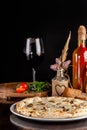 The concept of Italian cuisine. Thin cheese pizza with mushrooms, with large sides of Semola flour. A string of red wine