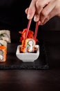 The concept of Japanese cuisine. A girl holds a red Chinese chopsticks and eat sushi in a restaurant. background image. Popular Royalty Free Stock Photo