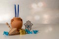 Concept of of jewish religion holiday hanukkah with wooden spinning top toy dreidel, hamsa, candles and chocolate coins over