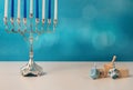 concept of of jewish holiday hanukkah with wooden spinning top toys dreidel and traditional chandelier menorah and candles