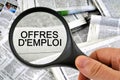 Job offers written in French studied with a magnifying glass