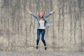 Concept of joy and freedom, life without problems. Crazy, extremely happy girl in jeans clothes and pink hat screaming and jumpin