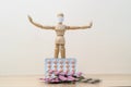 One wooden man mannequin in a protective medical mask holds his hands in different directions standing near a pile of medicine ta