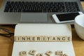 Concept keyword inheritance in wooden tile letters in personal home desk setting with laptop, notebook and accessories